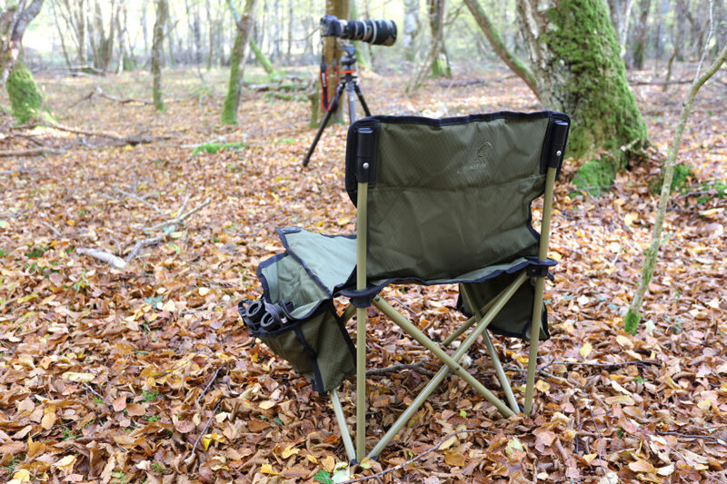 pixelpenguin- Een Koklass stoel klapstoel in het bos met een camera erop.