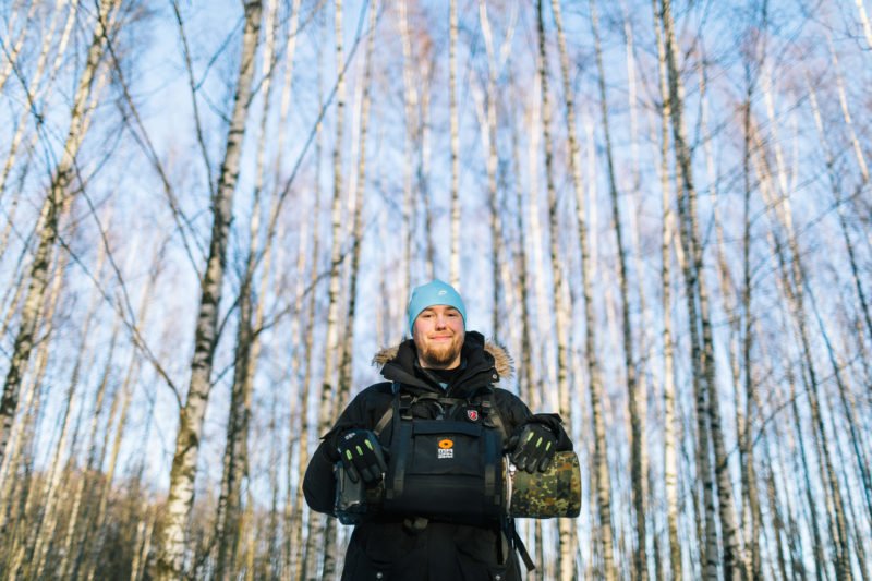 pixelpenguin- Een man die in een bos staat met een lensdrager.